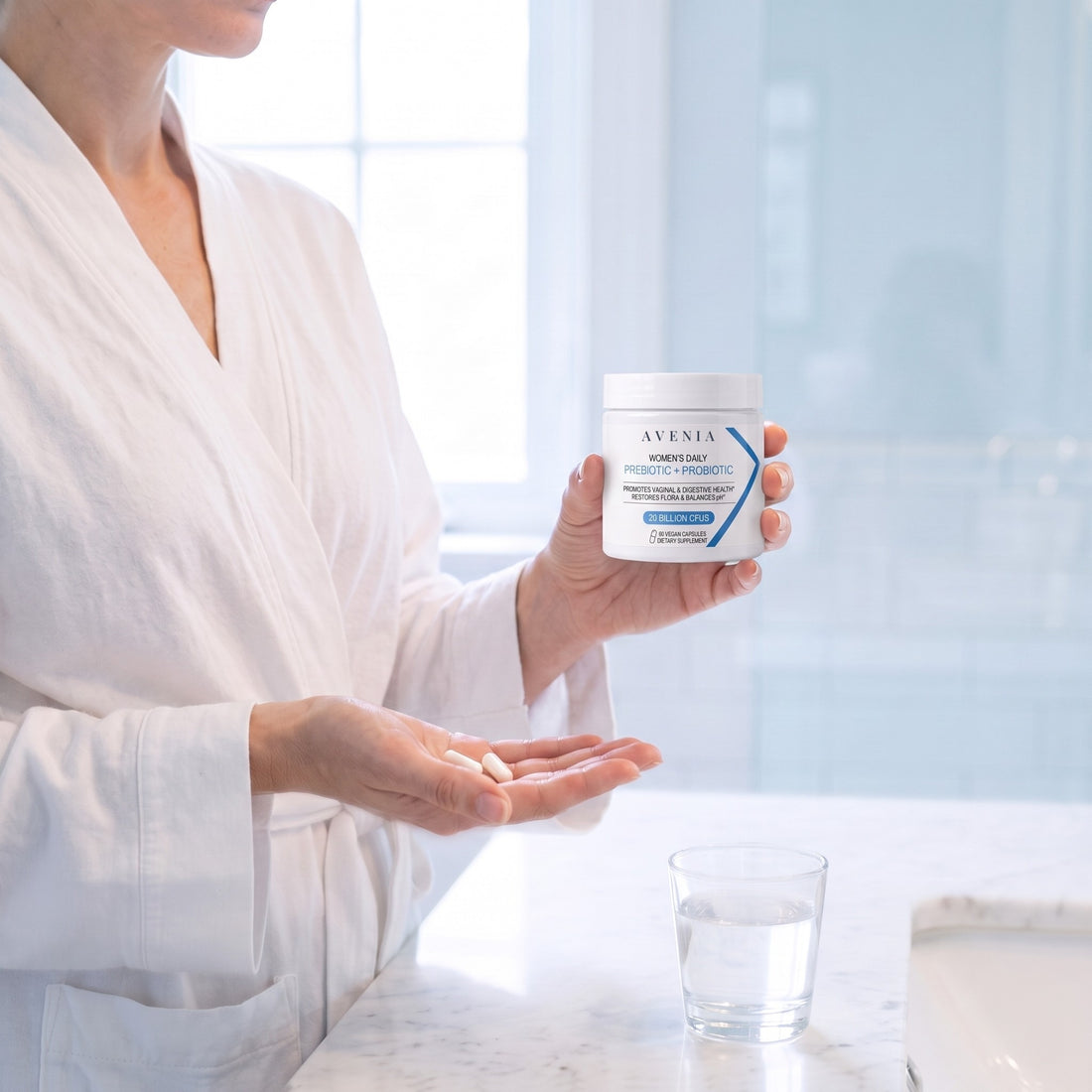 Woman holding a jar of AVENIA with two capsules in her hand