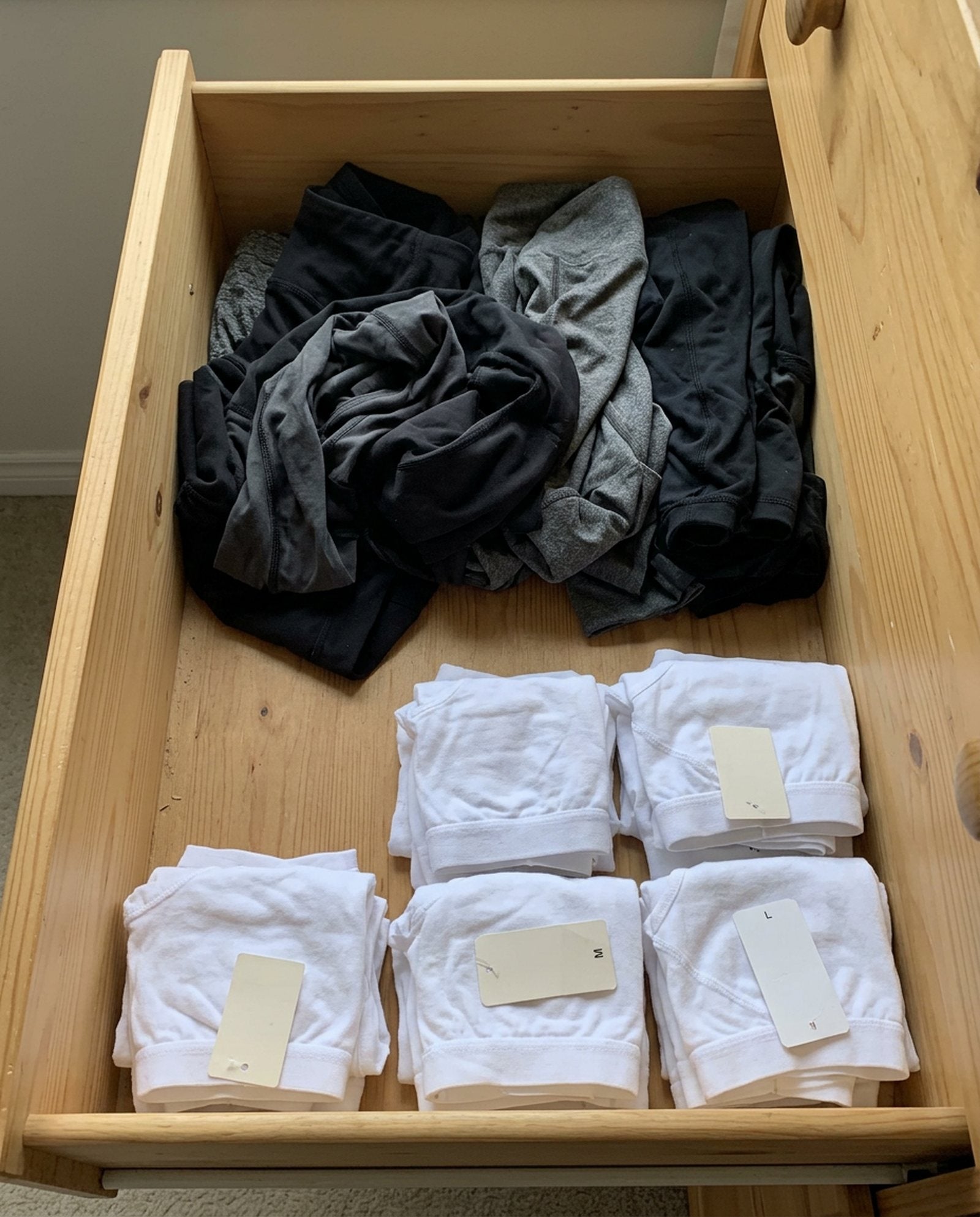 Leggings bunched at the back of a drawer, new cotton underwear with tags in front.