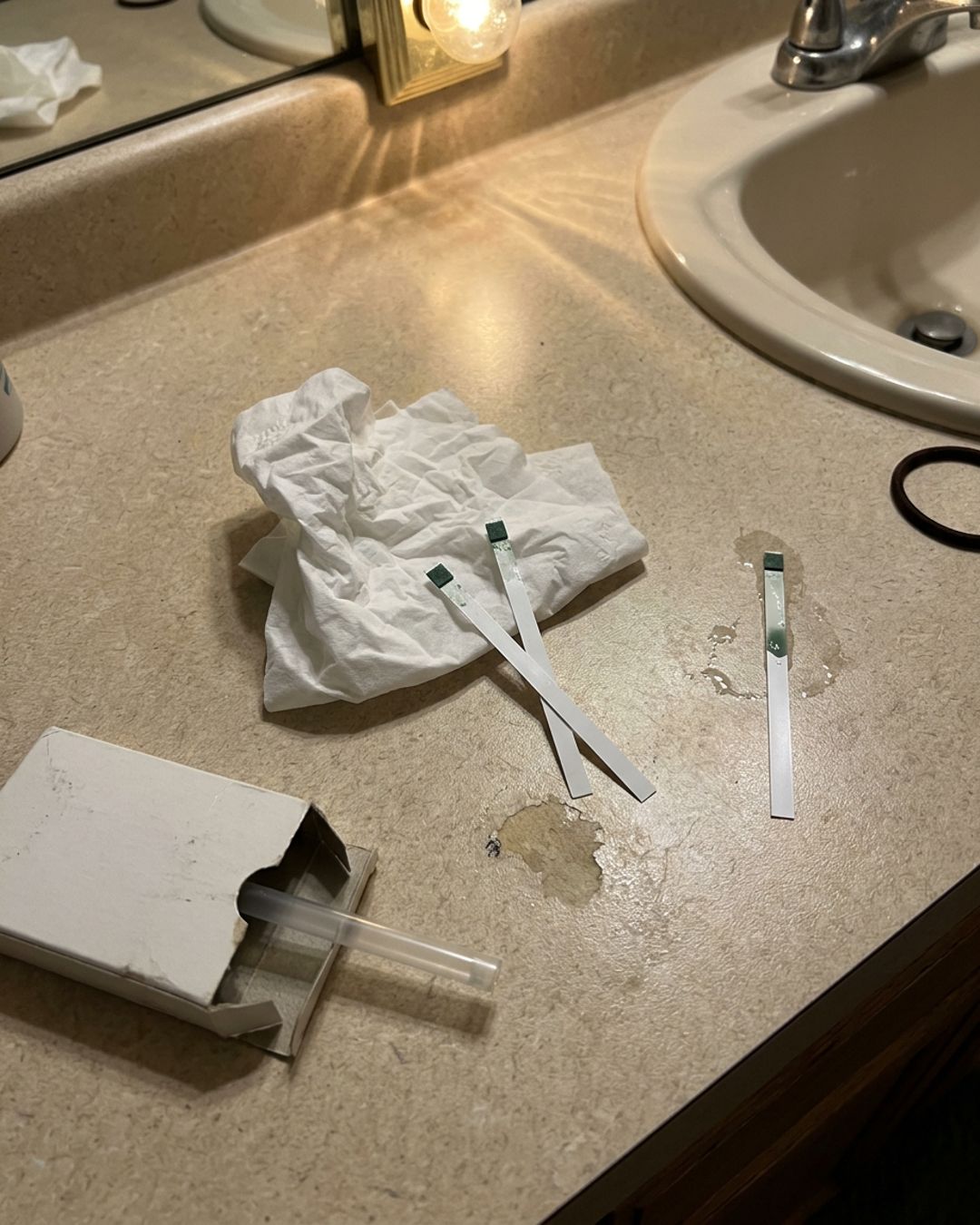 Used pH test strips and a crumpled tissue on a bathroom counter